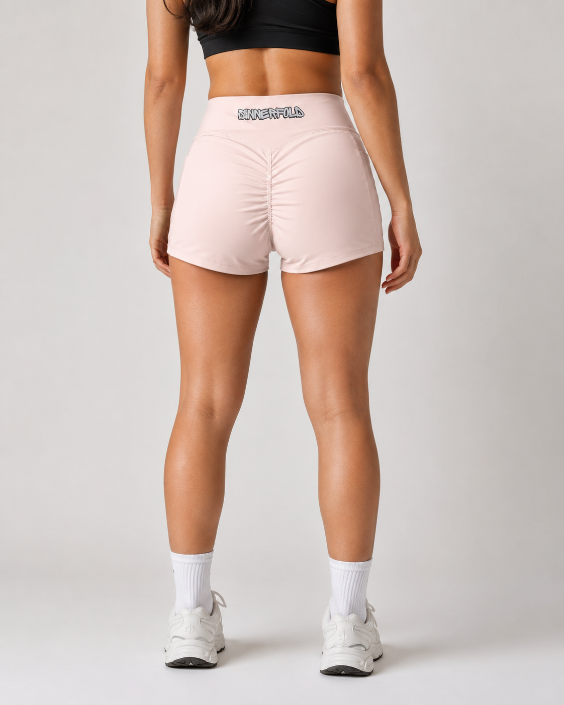 Person wearing pink athletic shorts with a visible brand logo on a plain background