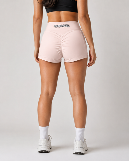 Person wearing pink athletic shorts with a visible brand logo on a plain background
