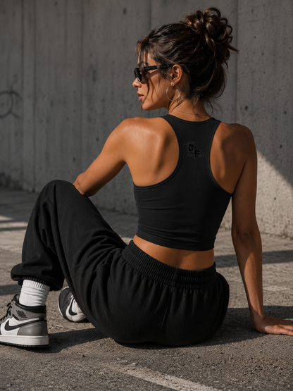 Woman in black athletic wear sitting on the ground against a concrete wall.