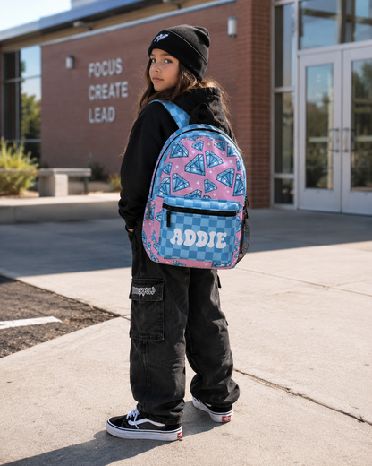Child wearing a backpack with 'ADDIE' on it in front of a building.