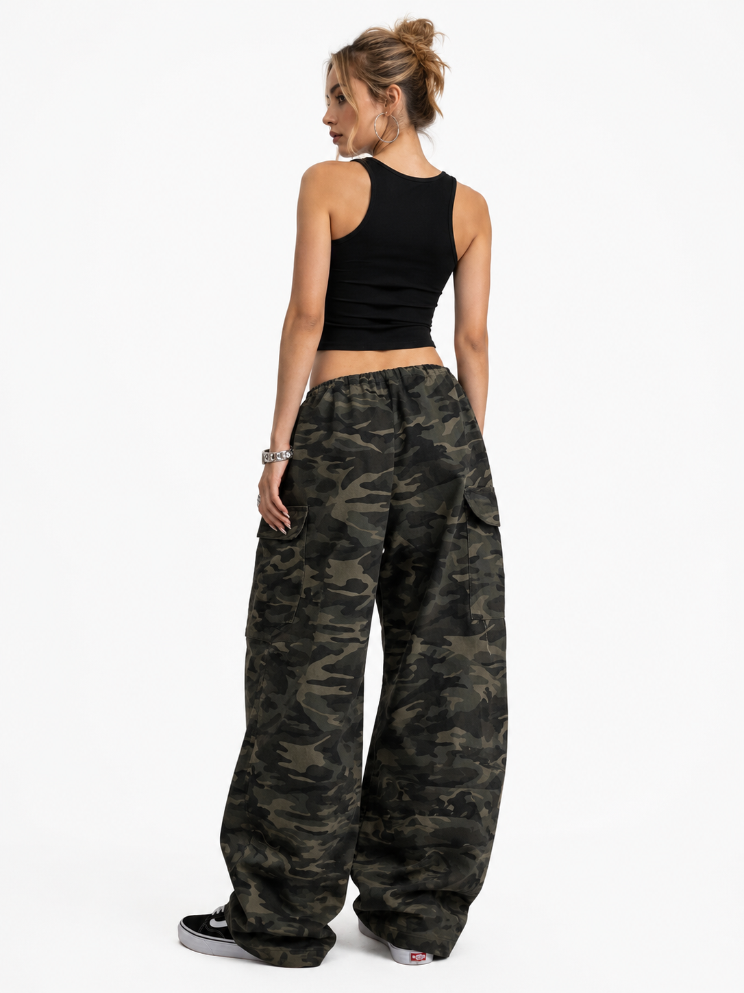 Woman wearing camouflage pants and a black top on a white background