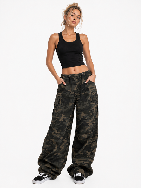 Woman wearing black tank top and camouflage pants on a white background