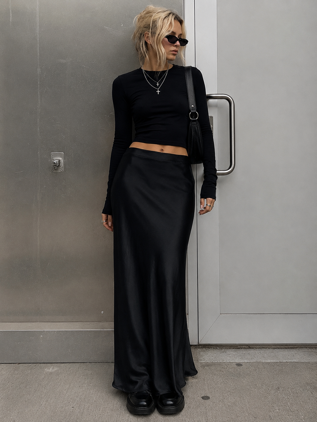 Person wearing a black outfit standing against a gray wall.