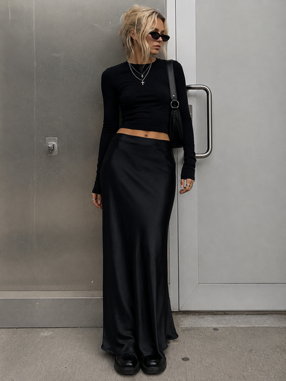 Person wearing a black outfit standing against a gray wall.