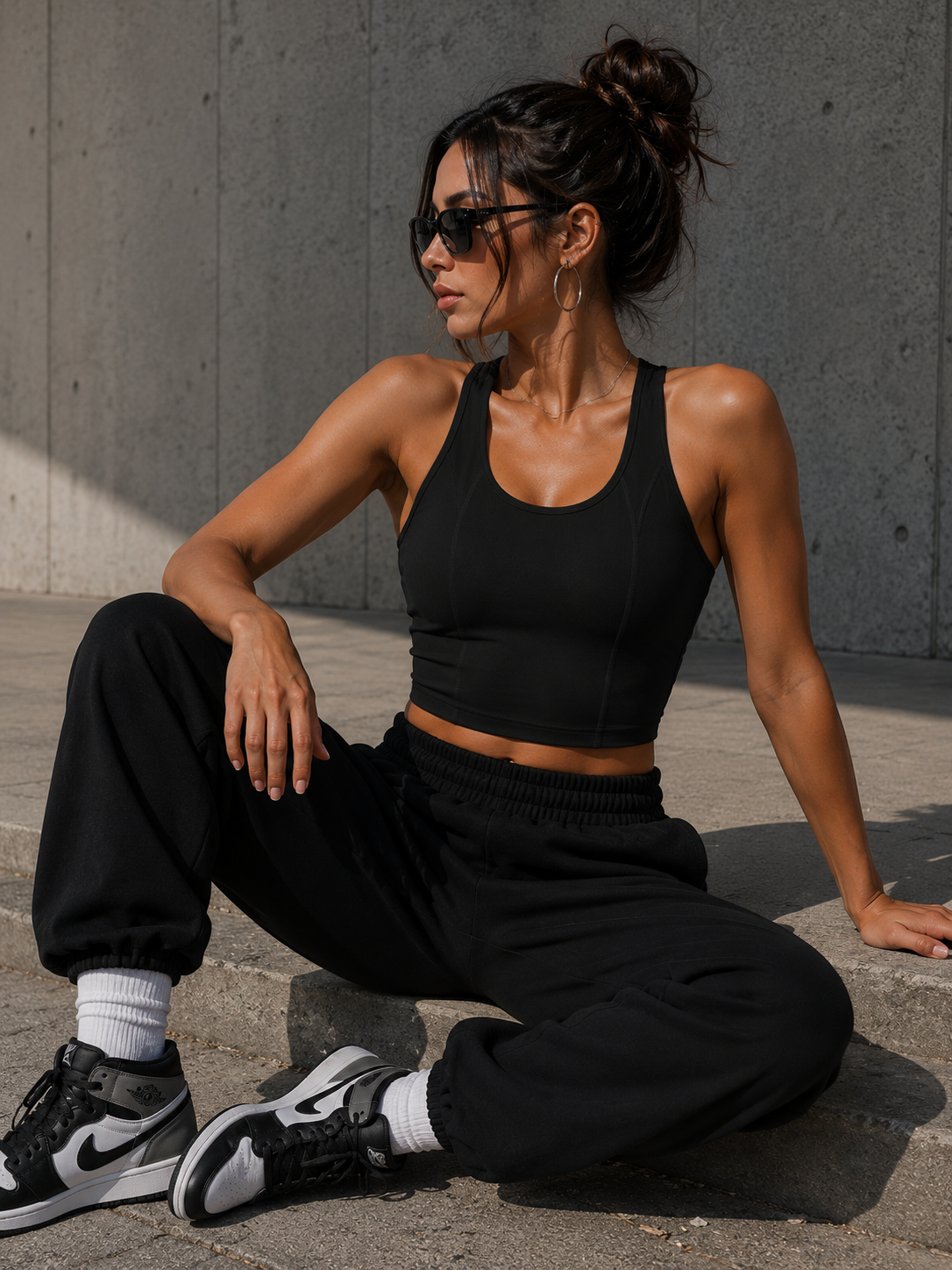 Woman in black athletic wear sitting on a concrete surface.