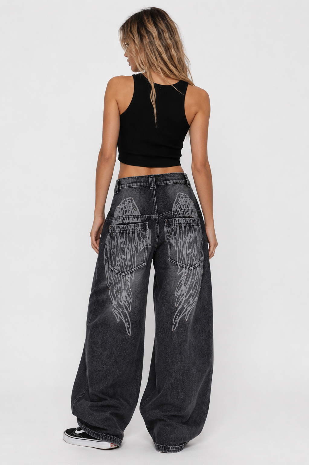 Woman wearing black wide-leg jeans with white designs on a white background