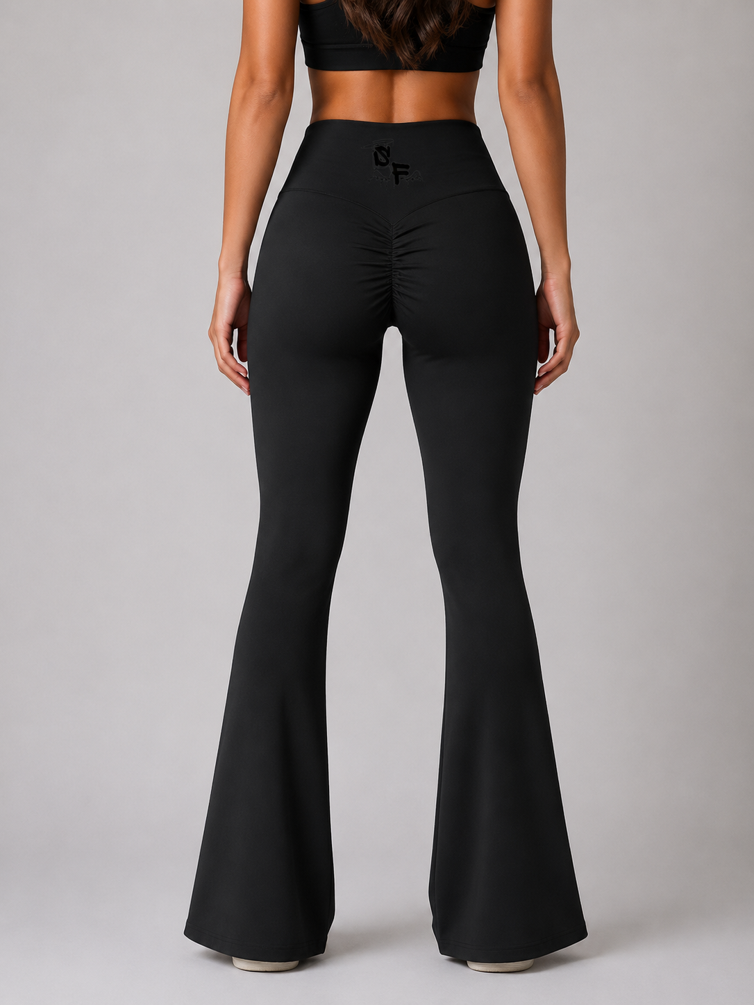 Black flared pants worn by a model on a gray background