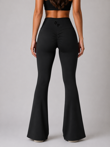 Black flared pants worn by a model on a gray background