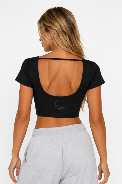 Woman wearing a black crop top with thin straps and gray sweatpants on a white background