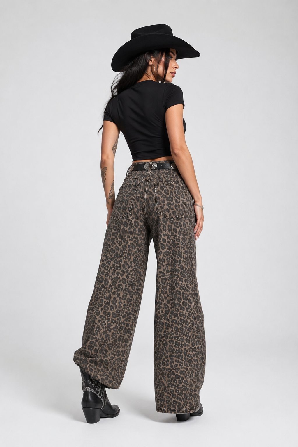 Person wearing leopard print pants and a black cowboy hat on a white background