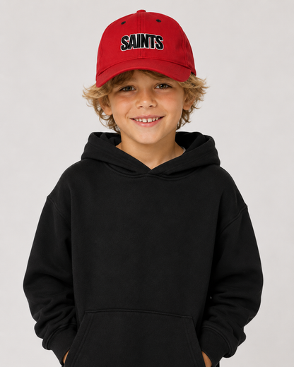 Child wearing a black hoodie and red cap with 'SAINTS' text on a light gray background