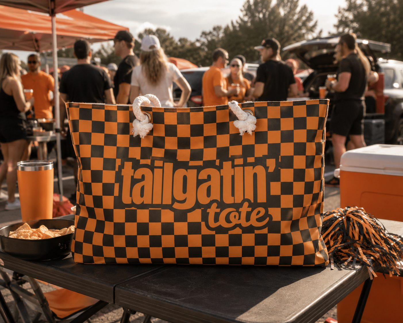Checkered 'Tailgatin Tote' bag on a table with people and food in the background