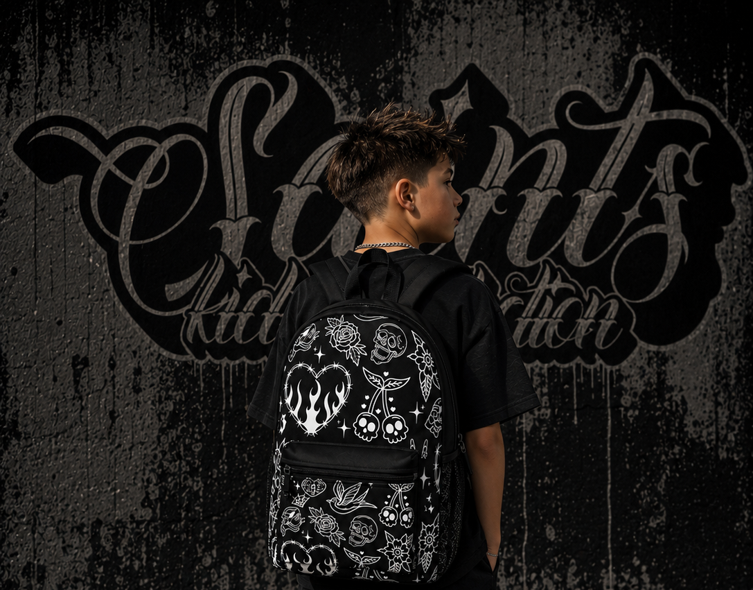 Person wearing a black outfit with a decorative backpack against a dark wall with graffiti.