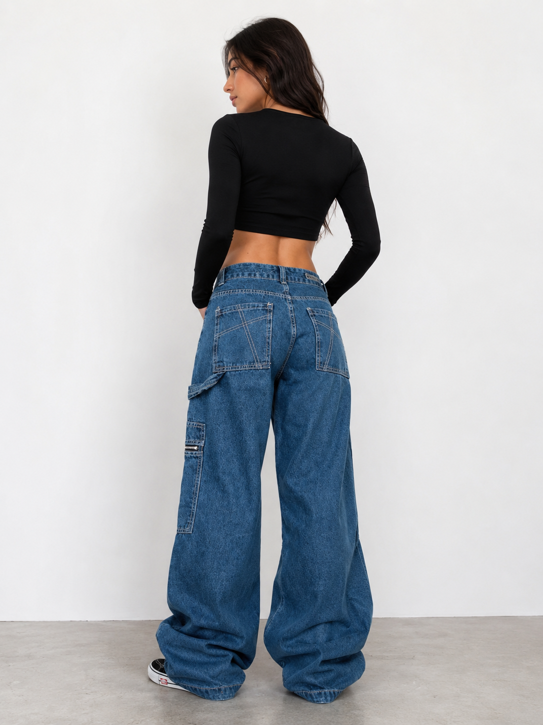 Person wearing blue jeans and a black crop top on a white background